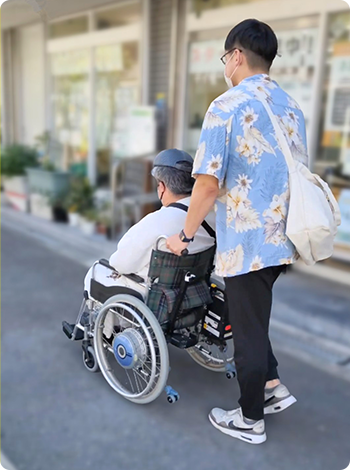 男性スタッフが入居者の車いすを押している様子